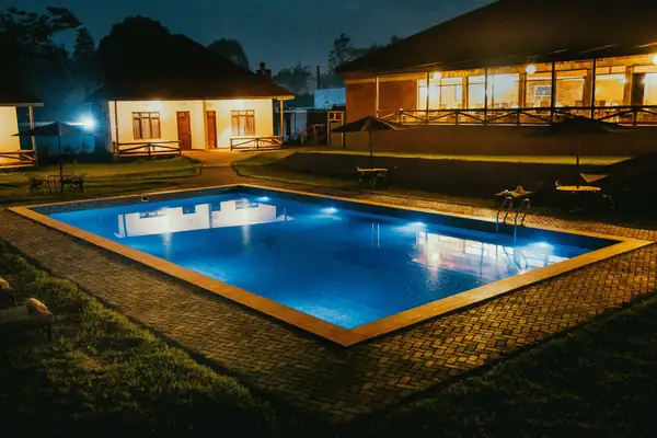 The swimming pool lit up at night in front of the villas and main building