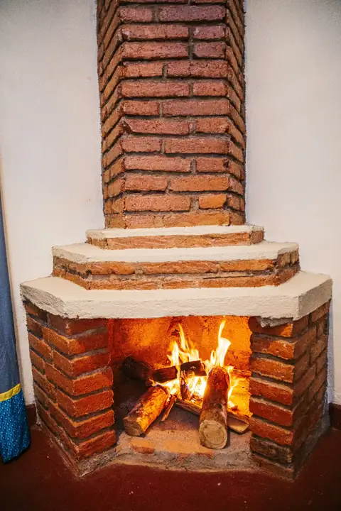 Brick corner fireplace with a fire burning