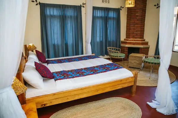 Room with beds under mosquito nets, blue curtains and a brick fireplace